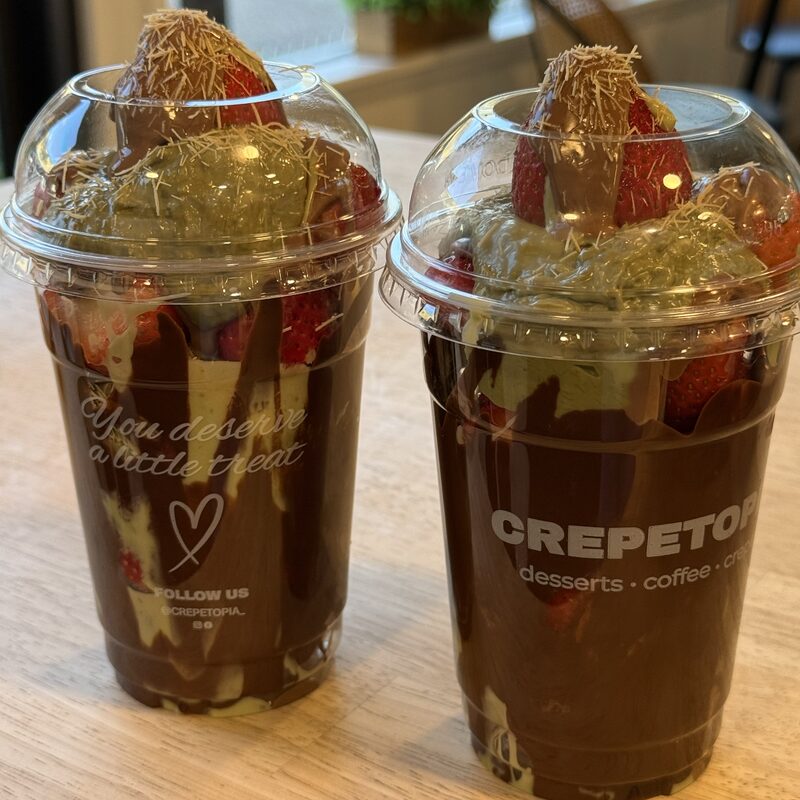 Two Dubai Strawberry Cups layered with chocolate, pistachio cream, and fresh strawberries, topped with toasted kataifi