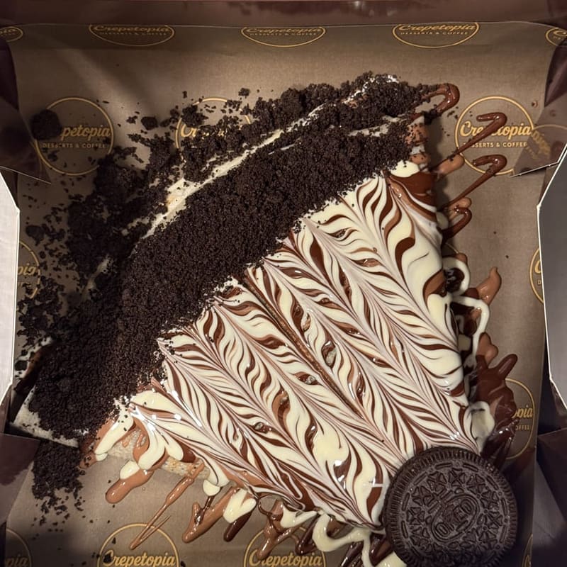 Oreo Crêpe topped with Oreo crumbs, a chocolate and white chocolate swirl, and a whole Oreo